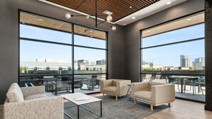 A modern office space with large windows, a high ceiling, and contemporary furniture. - Luxury Music Row Condo | King Bed & Balcony (Nashville)