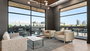 A modern office space with large windows, a high ceiling, and contemporary furniture.