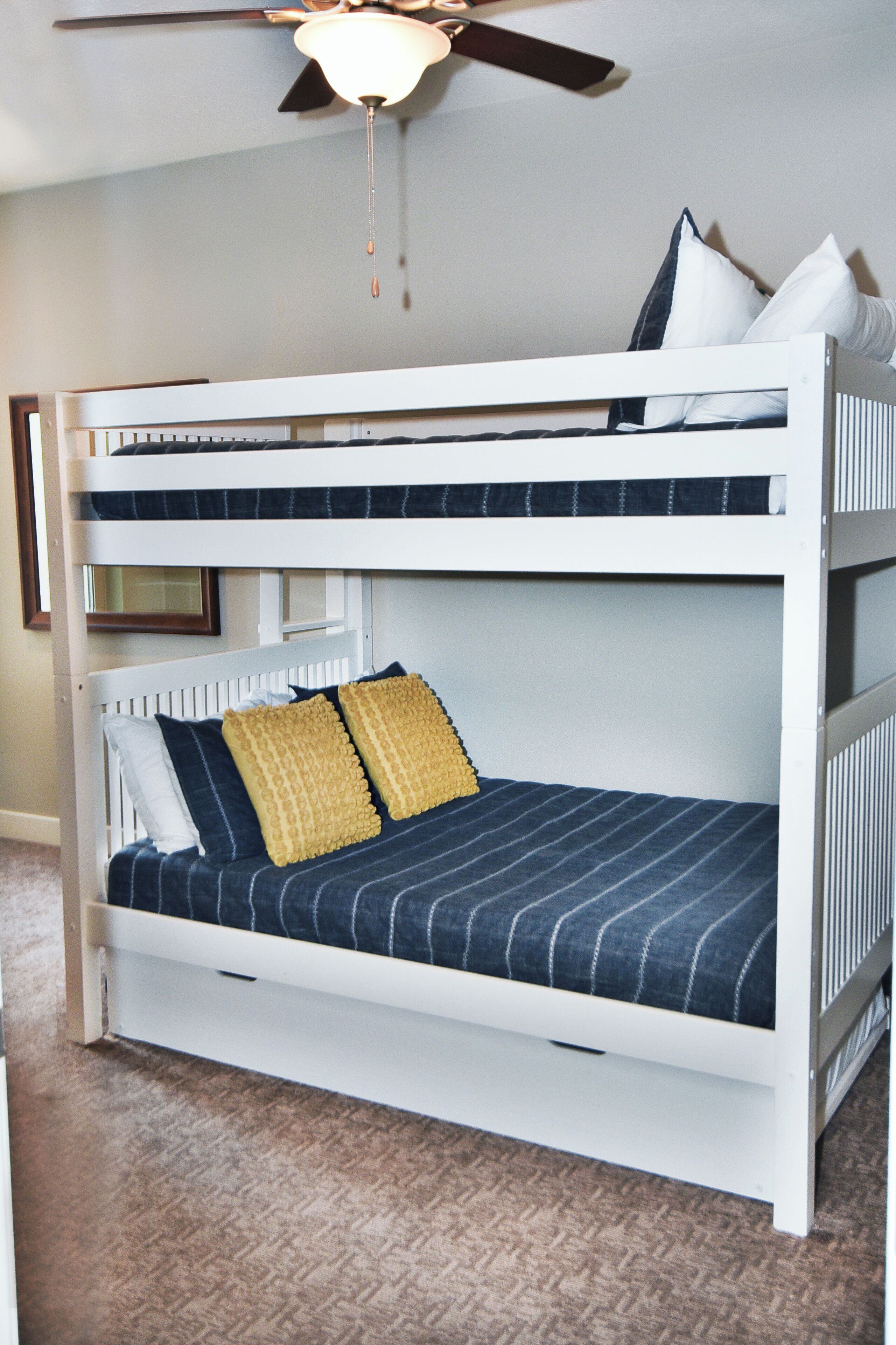 A bunk bed with two levels, a ceiling fan, and a framed picture on the wall.