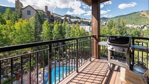 A balcony with a grill, overlooking a swimming pool and a mountainous landscape. - Highlands Lodge 403 Penthouse (Beaver Creek)