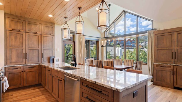 A spacious kitchen with wooden cabinets, a marble countertop, and pendant lighting. - Highlands Lodge 403 Penthouse (Beaver Creek)