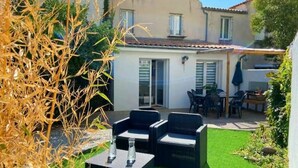 Une terrasse avec des meubles d’extérieur, une petite table et un espace abrité avec des chaises.