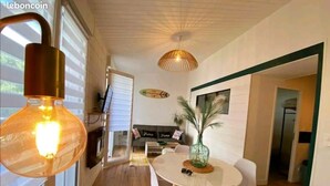 Un espace repas moderne avec une table ronde et des chaises, un luminaire suspendu et une décoration murale représentant une planche de surf.