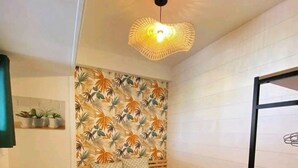 Une chambre à coucher de taille modeste, dotée d’une tête de lit à motifs, d’un lit recouvert d’une couvre-lit à motifs et d’un luminaire suspendu.
