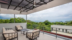 A balcony with a view of lush greenery and a distant island. - Los Mangos #3 • NEW! 3 BR Town-home • Private Plunge Pool Terrace, Coco Beach • Guests (Playa Hermosa)