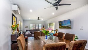 A modern dining area with a wooden table, six upholstered chairs, and a ceiling fan.