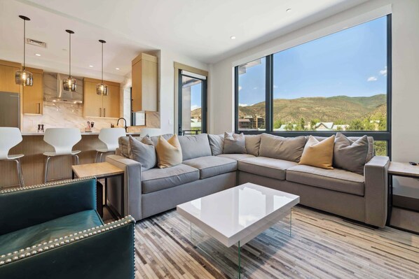 A modern living room with a sectional sofa, a coffee table, and a view of the outdoors.
