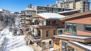 A modern multi-story hotel with balconies, large windows, and a snowy landscape. - One Riverfront Townhome 05 (Avon)