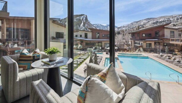 A modern hotel room with large windows, a pool, and a mountain view. - One Riverfront Townhome 05 (Avon)
