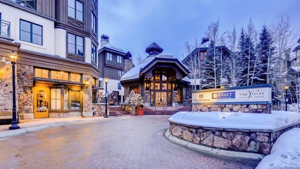 A hotel with a stone facade, a sign for The Villas, and a snow-covered entrance.