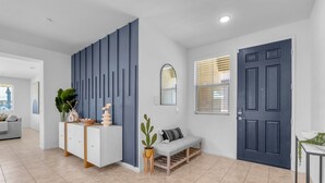 A modern living room with a grey sofa, a white cabinet, and a blue accent wall. - Agave House ~ Free Pool and Spa 🏊‍♀️ Heat  🐕 Pets Welcome !  Onsite ⛳️🎾 (Indio)