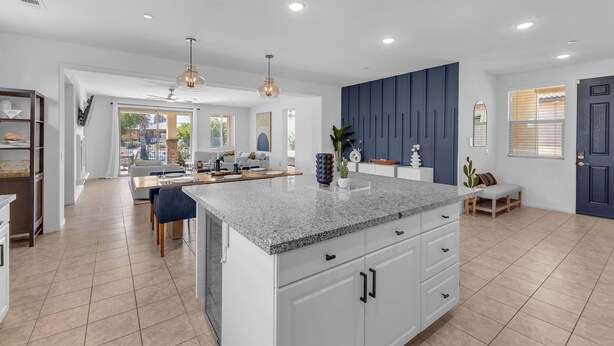 A modern kitchen with a granite countertop, white cabinetry, and a dining area with a table and chairs. - Agave House ~ Free Pool and Spa 🏊‍♀️ Heat  🐕 Pets Welcome !  Onsite ⛳️🎾 (Indio)