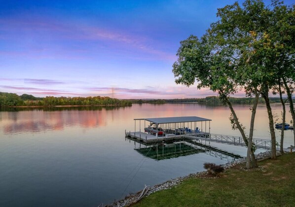 A calm lake with a dock, a covered seating area, and trees. - *Rare Find* Best Lot with Dock and Views on Lake (Winchester)