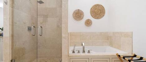 Une salle de bain avec une douche à parois de verre, un lavabo blanc et des meubles de couleur beige. Trois éléments décoratifs en fibres tressées ornent les murs.