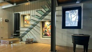 A modern interior with a wooden floor, a staircase with glass railings, a piano, and abstract art on the walls. - Ponte Milvio Luxury House (Rome)
