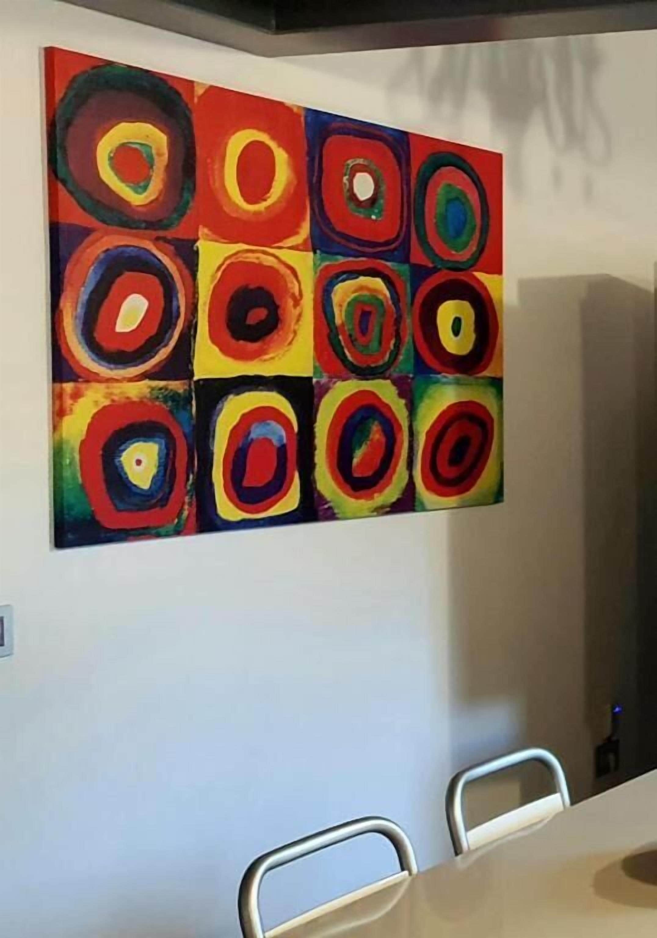 A room with a large abstract painting on the wall and a conference table with chairs.