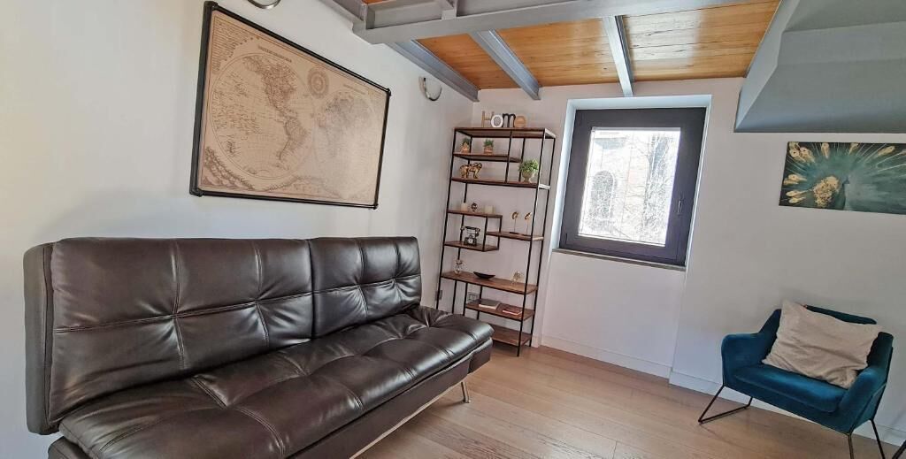 Een kamer met een bruine leren bank, een blauwe fauteuil, een houten boekenkast en een grote wereldkaart aan de muur.