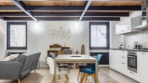 A modern kitchen with white cabinets, stainless steel appliances, and a wooden dining table with chairs. - Ponte Milvio Luxury House (Rome)