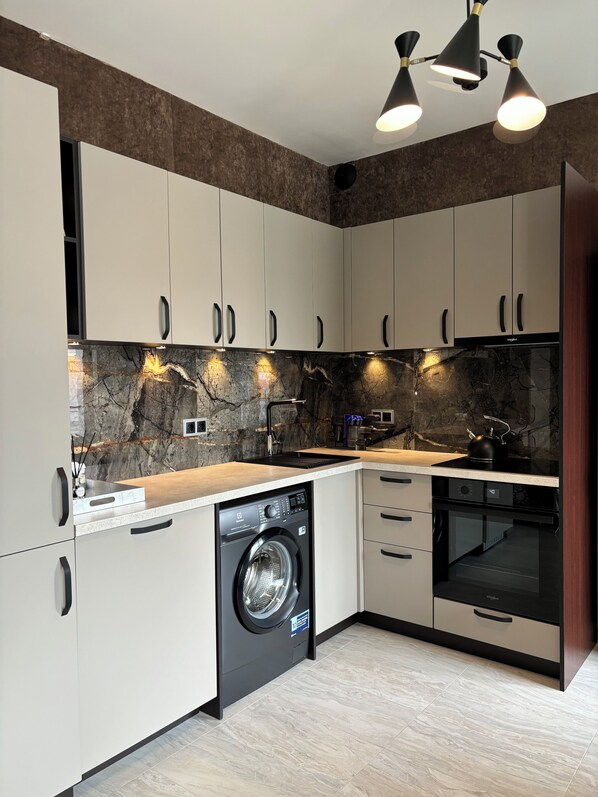 Enjoy cooking in this kitchen with sleek cabinetry, washing machine, and stainless steel sink.