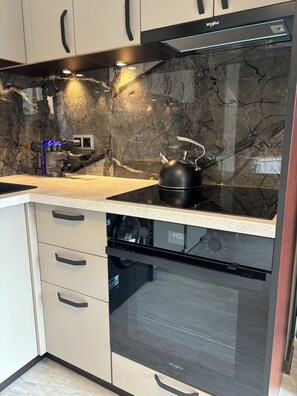Enjoy cooking in this well-equipped kitchen with a black induction cooktop, dishwasher, and microwave.