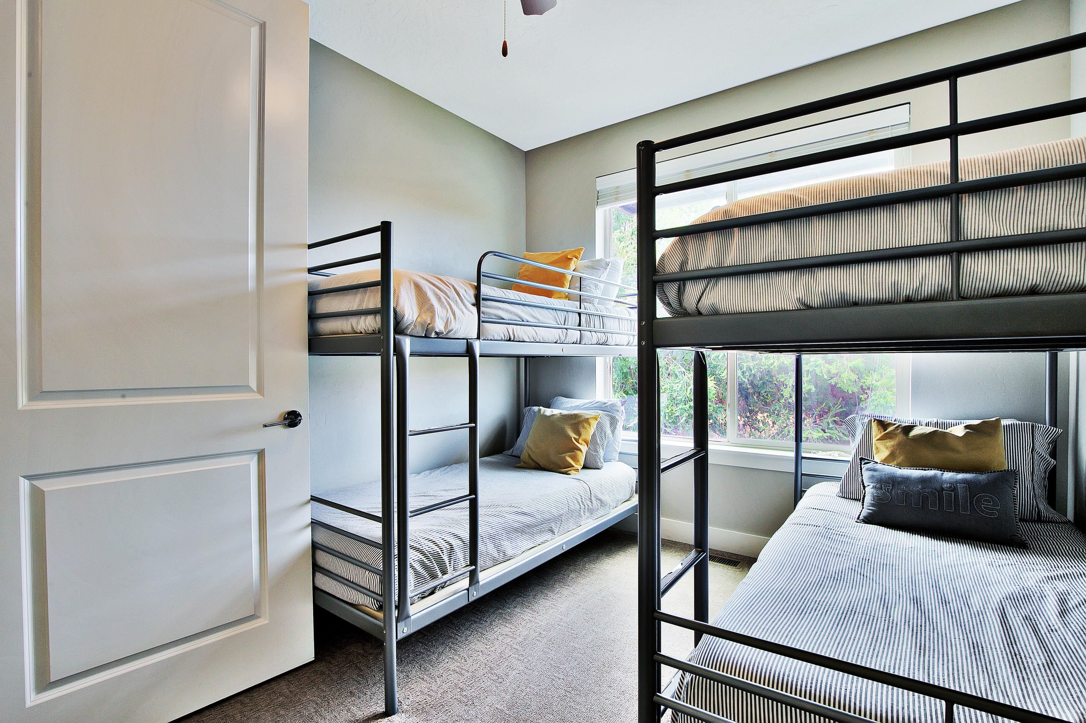 A dormitory room with bunk beds, a window with a view, and a door.