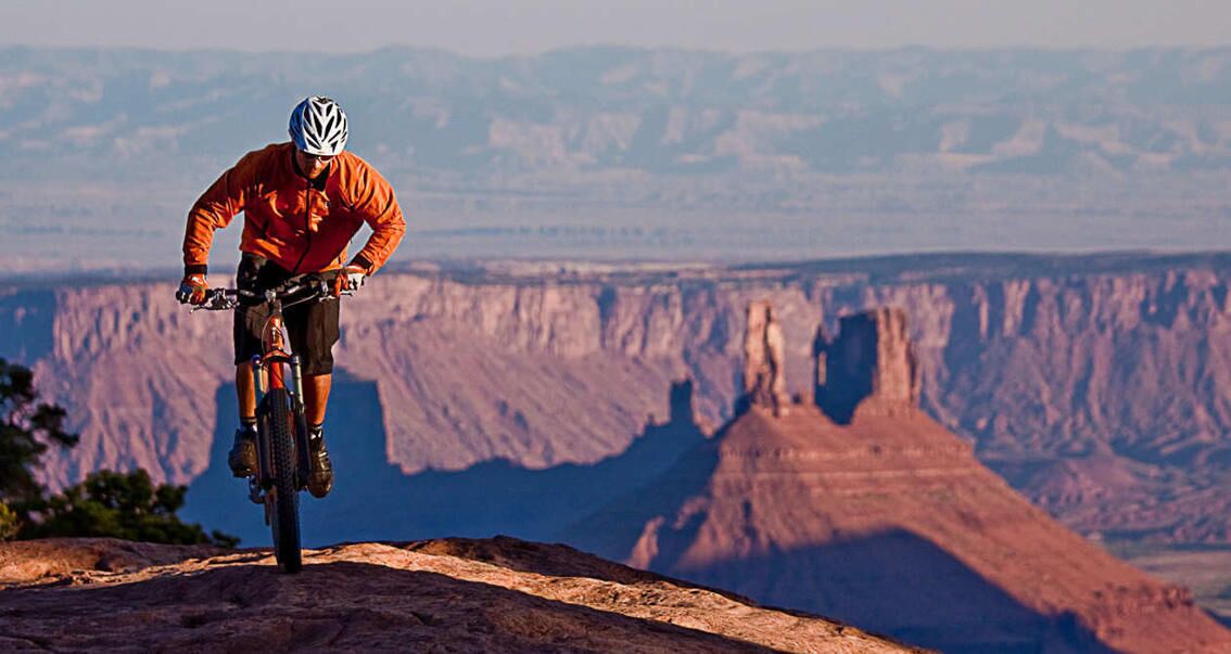 A mountain biker on a trail with a canyon in the background.