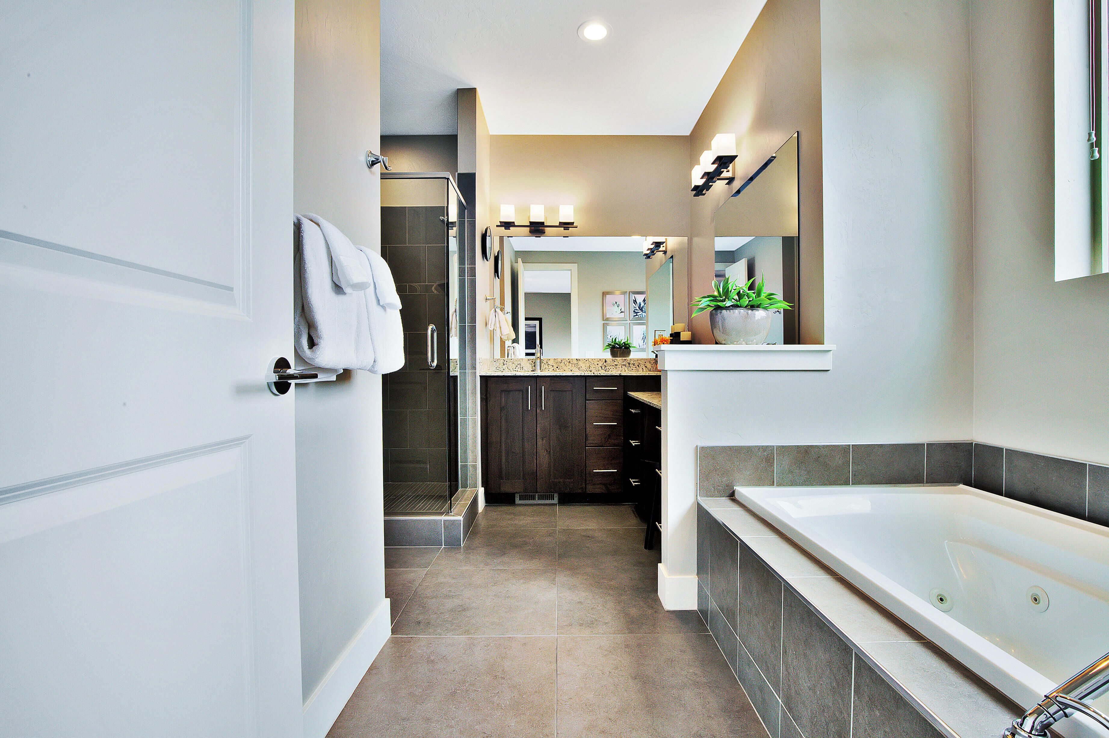 A modern bathroom with a walk-in shower, a bathtub, and a vanity with a mirror.