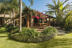 A garden with a wooden pergola, a bench, and lush greenery. - Santi Sabai Ibira - Um Refúgio às Margens da Lagoa (Imbituba)