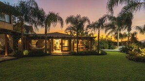 A well-maintained garden with a hammock, a covered seating area, and a pathway leading to a building. - Santi Sabai Ibira - Um Refúgio às Margens da Lagoa (Imbituba)