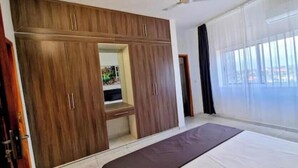 Une chambre à coucher avec un grand lit, une armoire et une fenêtre avec des rideaux.