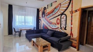 Un soggiorno con un divano blu scuro, un tavolino in legno e un affresco al muro.