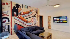 Una hall moderna con un grande murale raffigurante una figura egizia, una televisione a schermo piatto e un'area salotto con divano e tavolino.