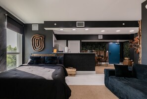Un dormitorio moderno con una cama grande, una kitchenette pequeña y vistas al exterior.