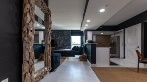 Ein modernes Wohnzimmer mit einem großen Spiegel, einer Couch und einer Küchenzeile mit einem Kühlschrank.