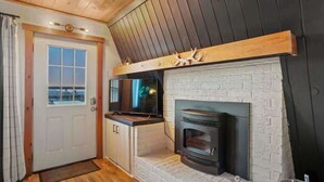 Una habitación acogedora con chimenea, televisión y puerta con vistas.