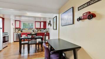 Una cocina moderna con armarios rojos, una zona de comedor con mesa y sillas, y un letrero en la pared que dice 'MOUNTAINS ARE CALLING'.