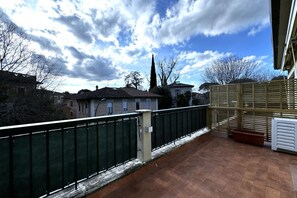 A balcony with a metal railing, a wooden fence, and a tiled floor. - Skyline Sunshine (Apartment with Terrace)   (Siena)