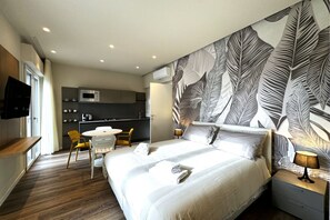 Une chambre d’hôtel moderne dotée d’un grand lit, d’un coin repas et d’une kitchenette.
