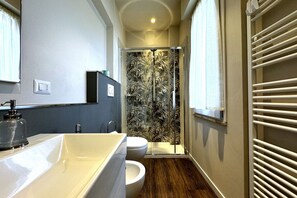Une salle de bain moderne dotée d’un grand lavabo, de toilettes et d’une douche en verre avec un motif de feuilles.