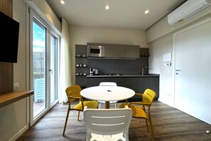 A modern kitchen with a microwave, stove, and sink. There is a dining table with four chairs. - Skyline Sunshine (Apartment with Terrace)   (Siena)