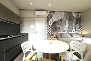 A modern kitchen with a stove, sink, and white chairs around a small table. - Skyline Sunshine (Apartment with Terrace)   (Siena)