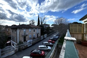 Une rue résidentielle bordée de voitures garées, une rangée de maisons et un ciel dégagé.