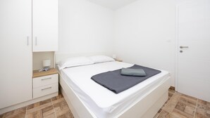 A bedroom with a bed, a bedside table, a lamp, a wardrobe, and a door.