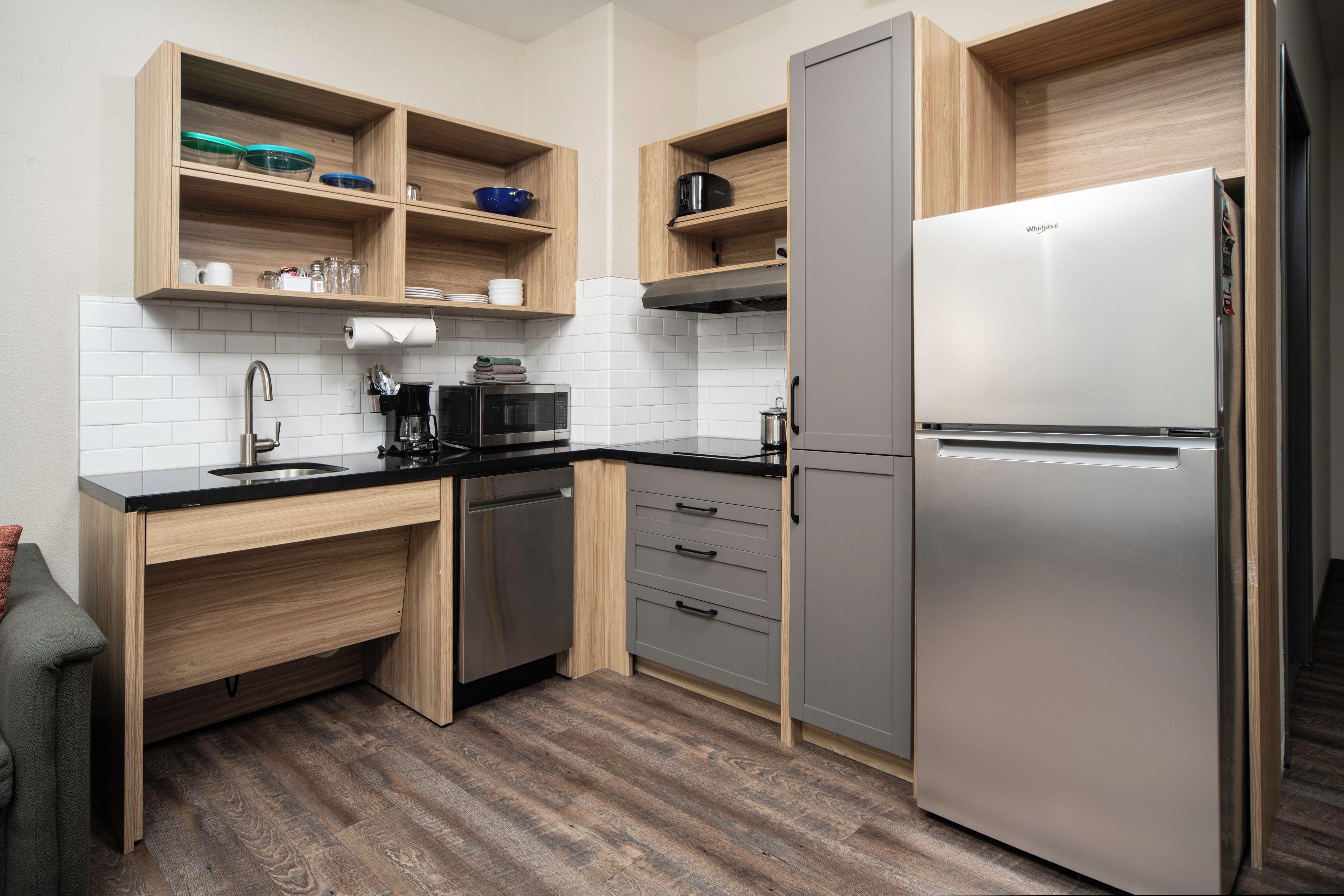 A modern kitchen with a built-in dishwasher, a stainless steel refrigerator, and wooden cabinetry.