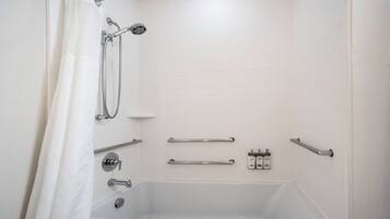 Een witte badkamer met een bad, douche en handgrepen.