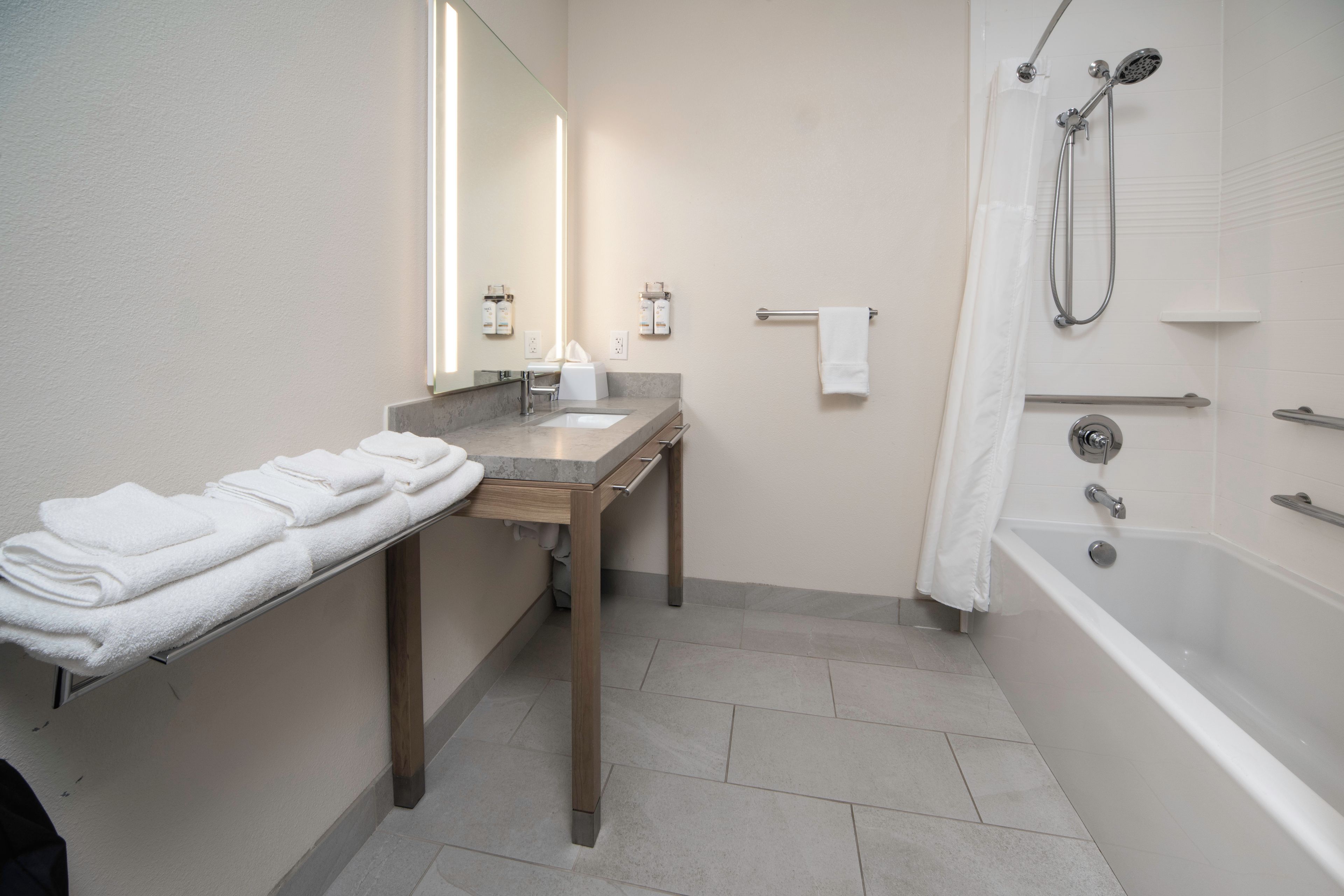 A bathroom with a sink, mirror, towel rack, and bathtub.