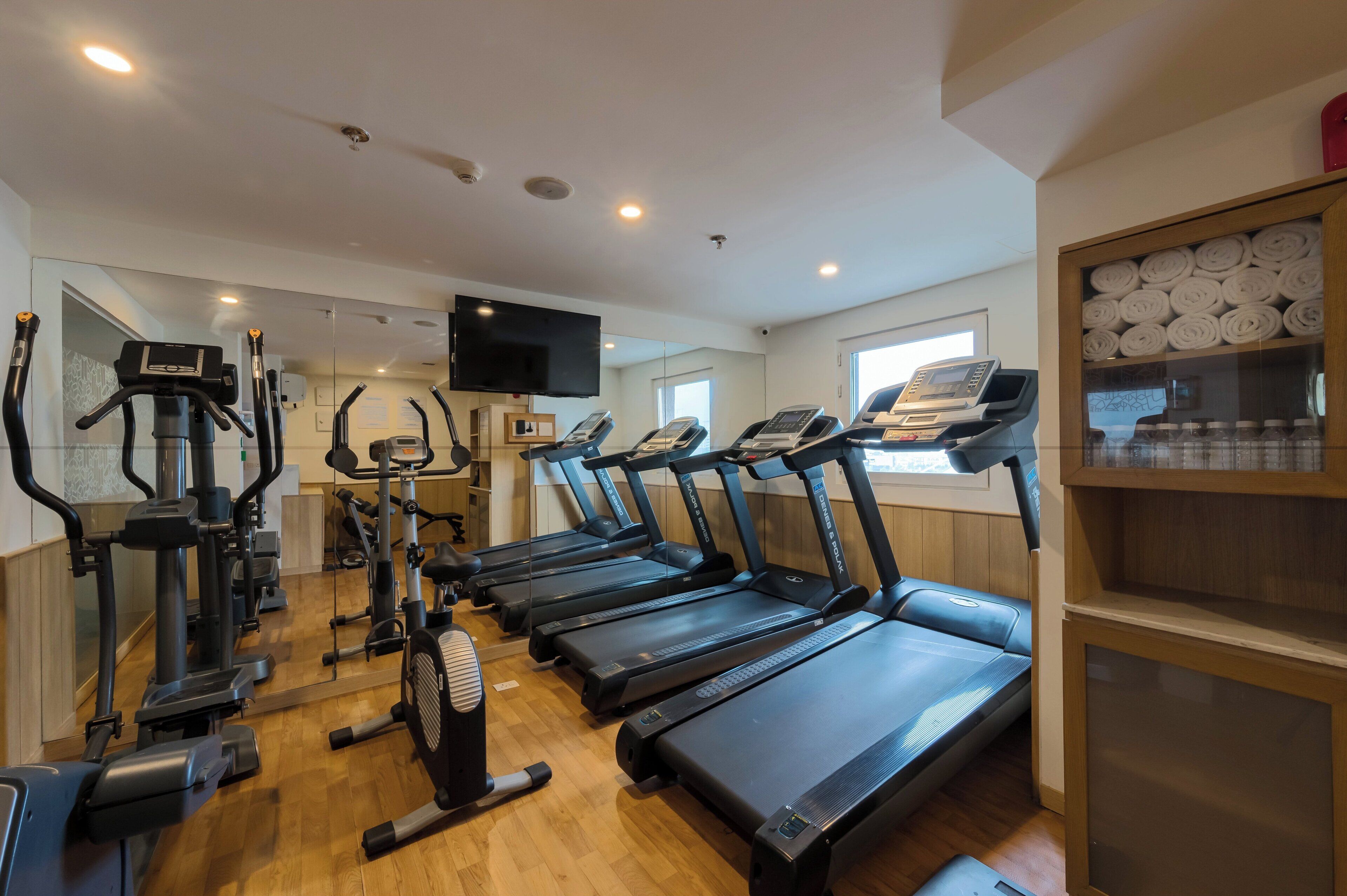 Un gimnasio con cintas de correr, elípticas y un ventilador.