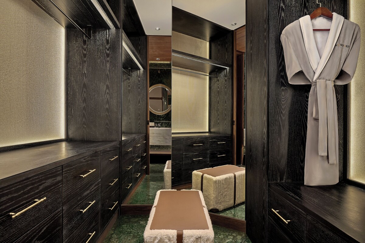 A luxurious bathroom with dark wood cabinetry, a mirror, and a robe hanging on the wall.