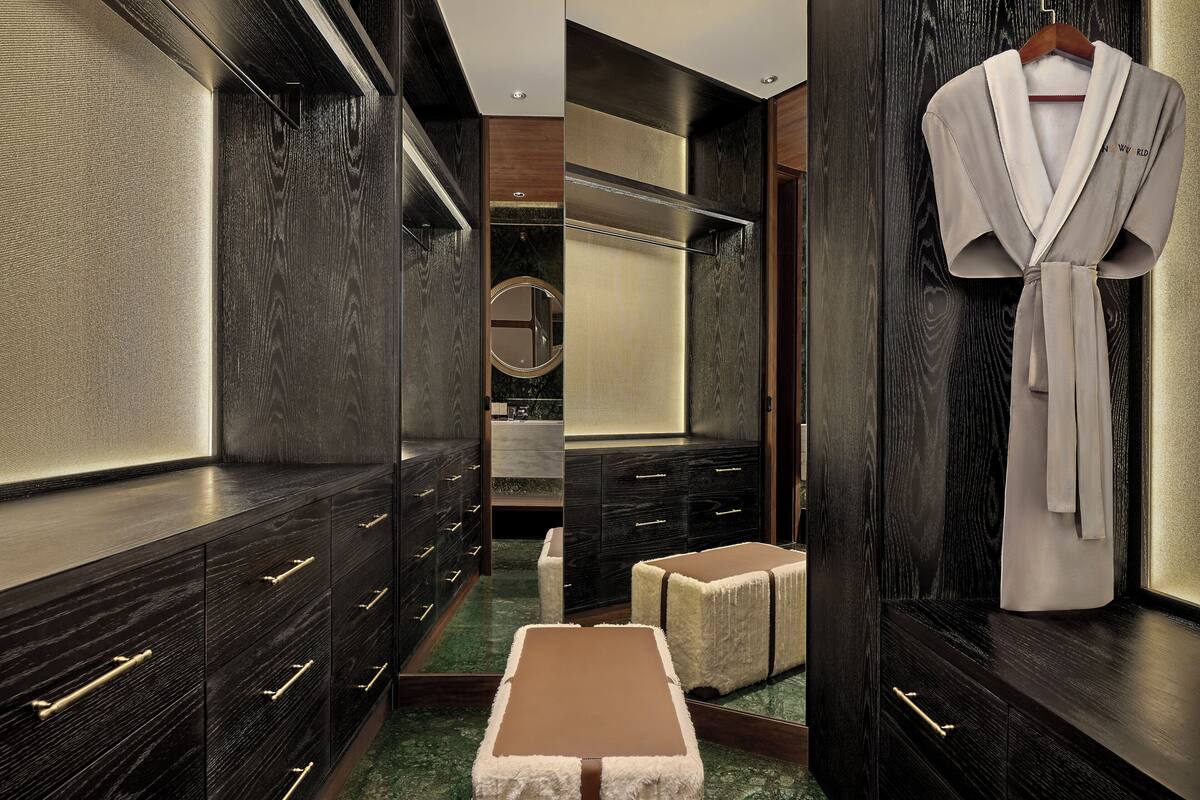 A luxurious bathroom with dark wood cabinetry, a mirror, and a robe hanging on the wall.