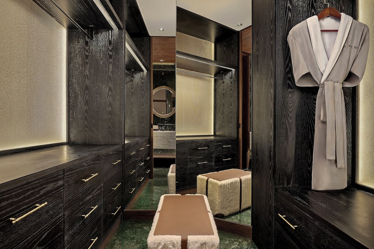 A luxurious bathroom with dark wood cabinetry, a mirror, and a robe hanging on the wall.